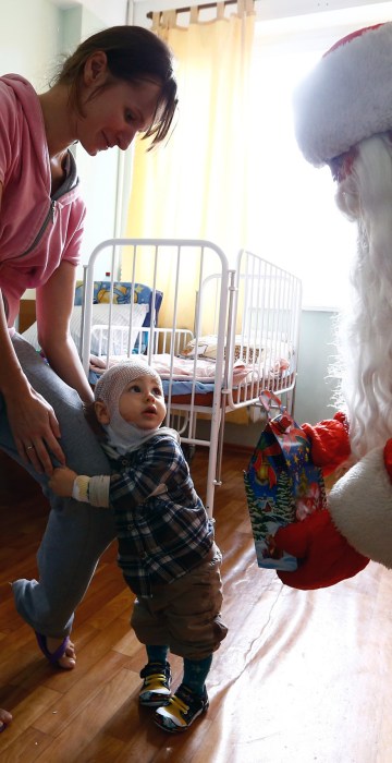 Image: A man dressed as Father Frost, equivalent of Santa Claus, gives a present to a boy on the eve of Christmas in a burn unit of a hospital in Minsk