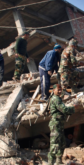 Image: Locals help Indian soldiers remove debris from a damaged building