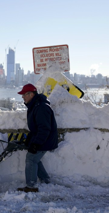 Image: A resident removes snow away from the entrance to his home in Union City