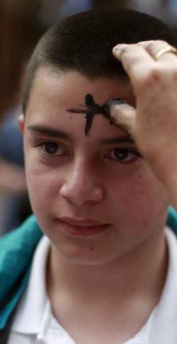 Image: A boys receives a cross of ashes during service