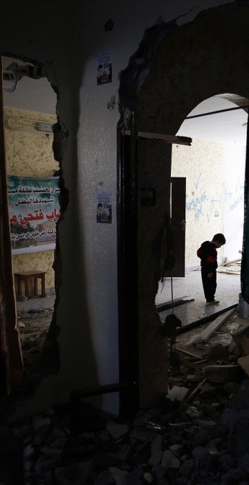 Image: A Palestinian child walks through the home of Ehab Maswada that was demolished by the Israeli army
