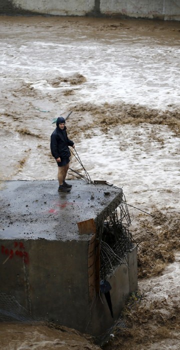Image: A man is seen next to a river during floods in Santiago