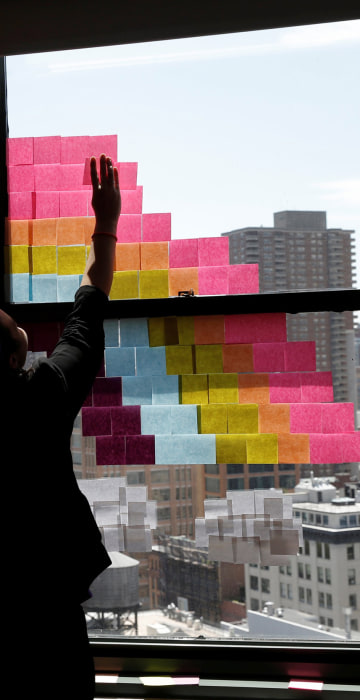 Image: Employee creates a rainbow image on a window with Post-it notes at the Horizon Media offices at 75 Varick Street in lower Manhattan, New York during \"Post-it note art war\"