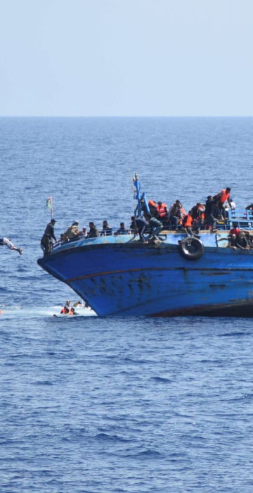 Image: Migrants are seen on a capsizing boat before a rescue operation by Italian navy ships \"Bettica\" and \"Bergamini\" (unseen) off the coast of Libya