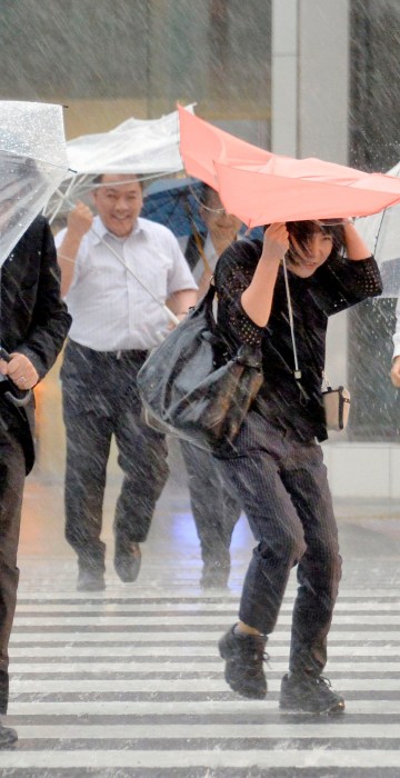 Image: Pedestrians holding umbrellas struggle against strong wind and heavy rains caused by Typhoon Malakas in Nagoya, central Japan