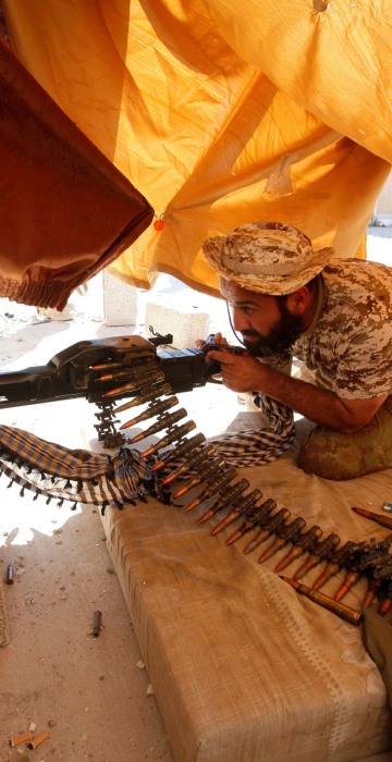 Image: Fighter from Libyan forces allied with the U.N.-backed government aims his weapon as he takes a position on a building rooftop during a battle with Islamic State militants in Sirte