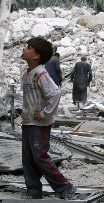 Image: A boy inspects a damaged site after airstrikes on the rebel held Tariq al-Bab neighbourhood of Aleppo