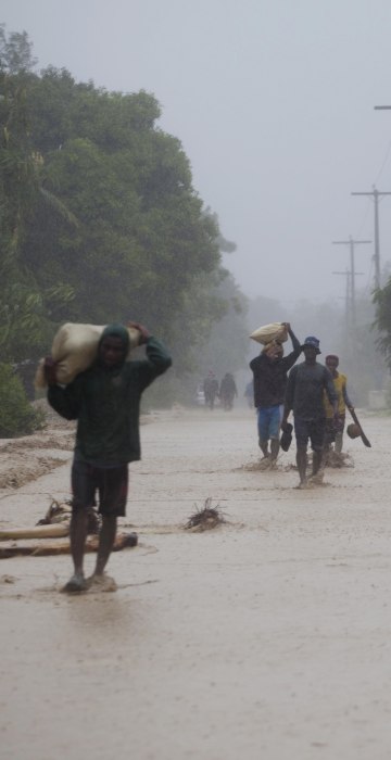Image: Residents walk in flooded streets as they return to their homes in Leogane, Haiti