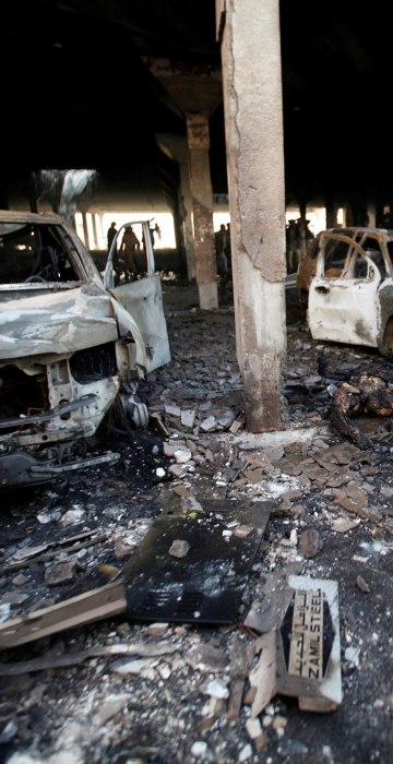 Image: People stand at the site of an airstrike which witnesses said was by Saudi-led coalition aircraft on mourners at a hall where a wake was being held, in Sanaa