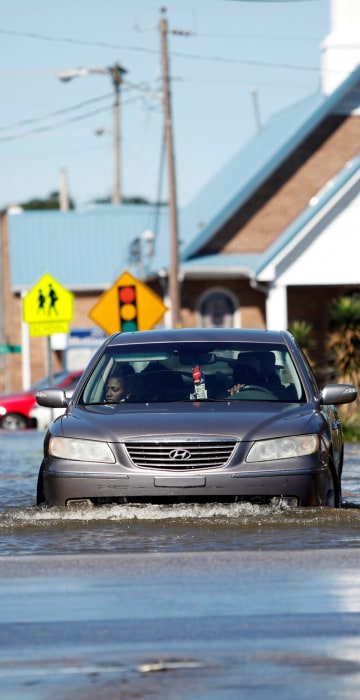 Image: A car navigates a flooded street off Highway 41 in Lumberton