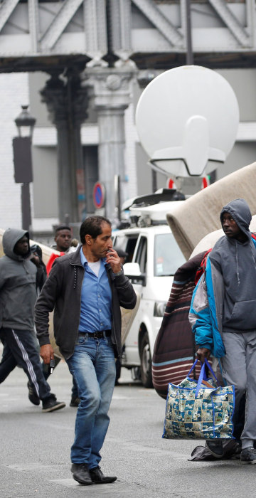 Image: Migrants move tents from a makeshift camp in a street near Stalingrad metro station in Paris