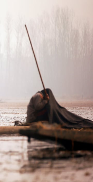 Image: Kashmiri fishermen cover their heads and part of their boats with blankets and straw as they wait to catch fish in the waters of the Anchar Lake on a cold day in Srinagar