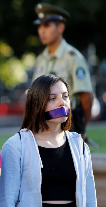 Image: Women cover their mouths as they attend a peaceful demonstration in front of the government house as part of International Women's Day, in Santiago