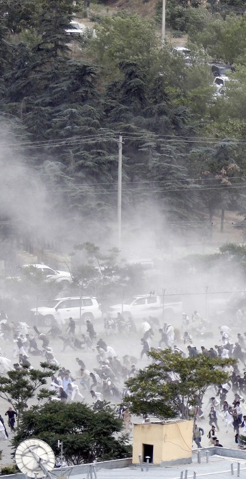 Image: Funeral goers break into a run after one of three suicide bombers detonated during the ceremony.