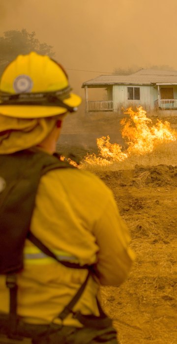 Image: Firefighters watch as flames surround a home in Mariposa on July 19.