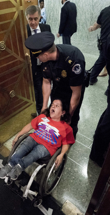 Image: A woman in a wheelchair is removed after disrupting a Senate Finance Committee hearing to consider the Graham-Cassidy health care proposal