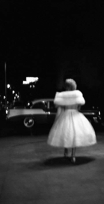 Image: A woman in a party dress walks towards a car in Miami, 1957.