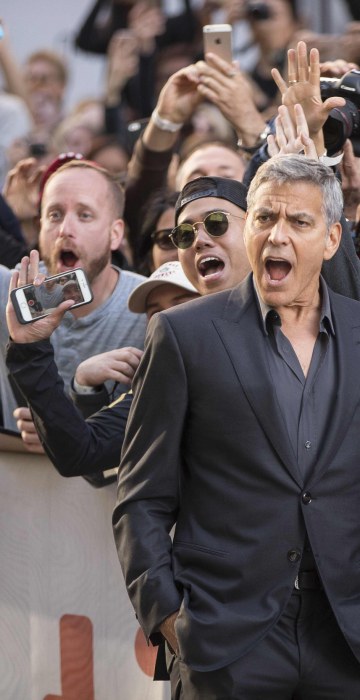 Image: George Clooney poses with fans at a film premiere