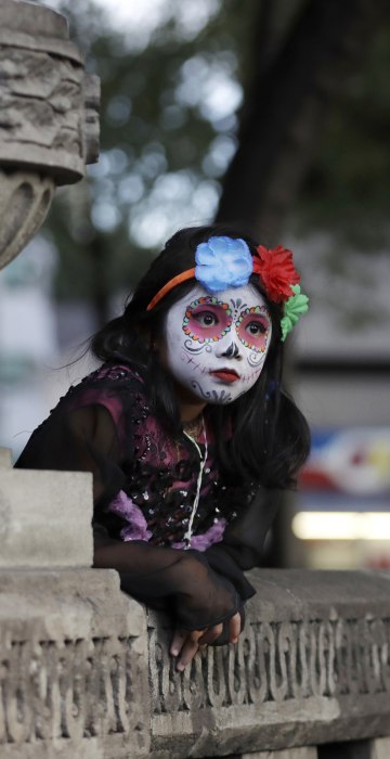 Image: A girl leans against stone benches as she awaits the start of the Grand Procession.