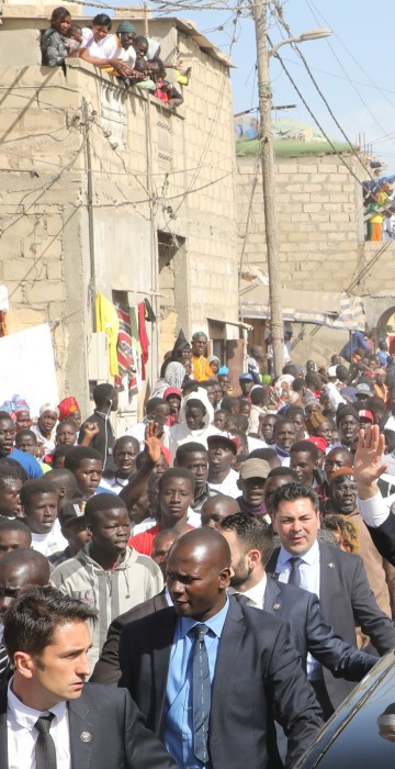 French President Emmanuel Macron and Senegalese President Macky Sall wave to the crowd in Saint-Louis on Feb. 3, the final day of Macron's visit to Senegal.