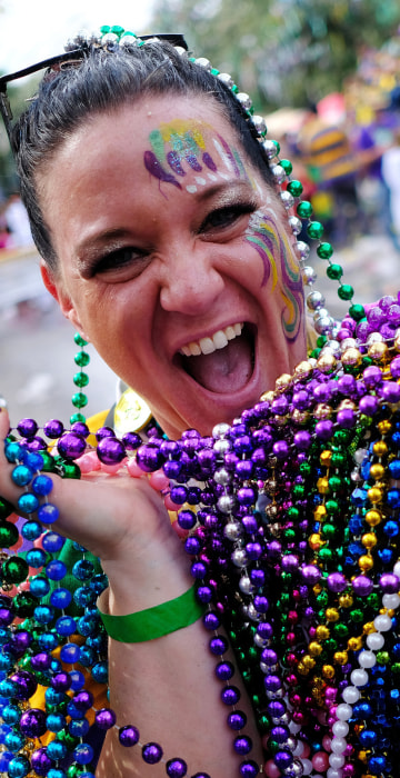 Karen Price shows off her catch of beads from the The Krewe of Thoth parade during Mardi Gras celebrations in New Orleans on Feb. 11, 2018.