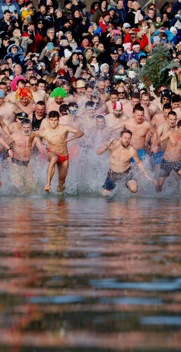 Image: Swimmers run into the chilly waters of Lake Balaton in Szigliget, Hungary.