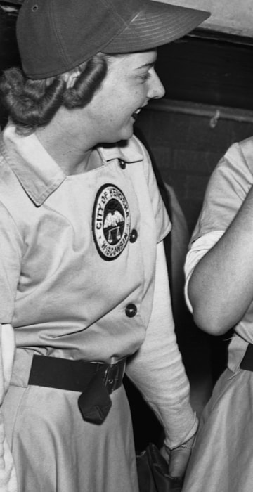 Elise Harney, pitcher for the Kenosha Comets, refreshes her makeup between innings as teammate Janice O'Hara and another player look on. The women of the All-American Girls Professional Baseball League were required to look their best whether on or off the field, and received \"charm school\" training to teach them how to maintain that feminine look.