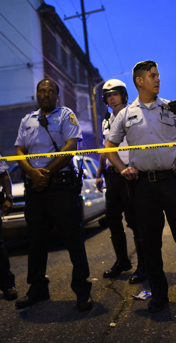 Police officers monitor activity near a residence while responding to a shooting in Philadelphia on Aug.14, 2019.