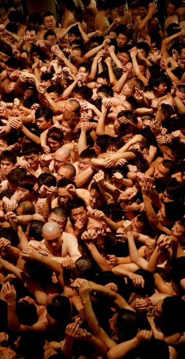 Image: Men dressed in loincloths prepare to snatch a wooden stick called \"shingi\" tossed by the priest during a naked festival at Saidaiji Temple in Okayama