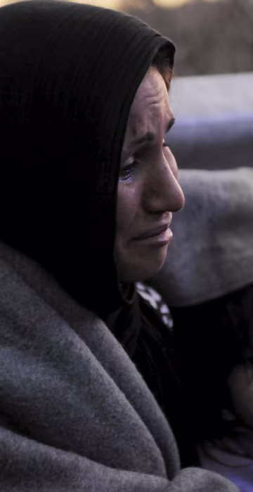 Image: An Afghan mother cries as she covers herself and her children with a blanket while trying to reach the Greek-Macedonian border, following reports that Macedonia has closed its borders with Greece to Afghan migrants
