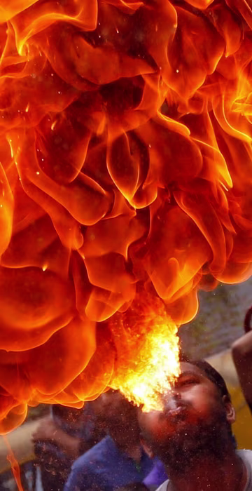 Image: A Hindu devotee performs a stunt with fire during a rehearsal for the annual Rath Yatra in Ahmedabad