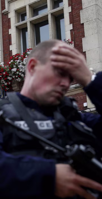 Image: A policeman secures the position in front of the city hall after two assailants had taken five people hostage in the church at Saint-Etienne-du -Rouvray near Rouen in Normandy