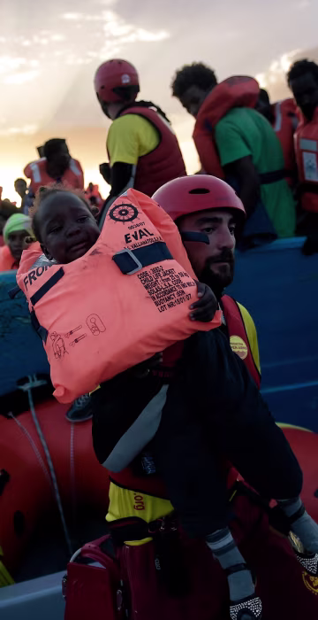 Image: A child from African origin is rescued from a distressed vessel by a member of Proactiva Open Arms NGO in the mediteranean
