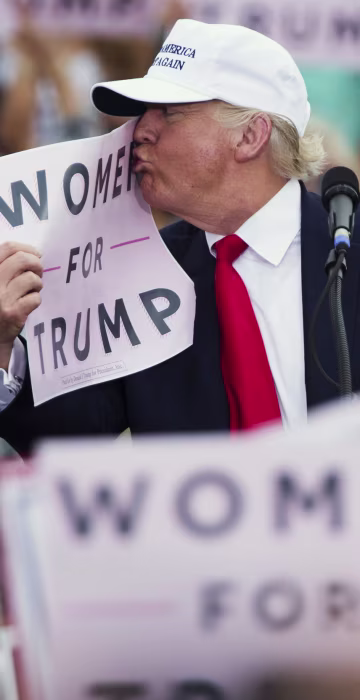 Image: Trump kisses a \"Women for Trump\" sign during a campaign rally
