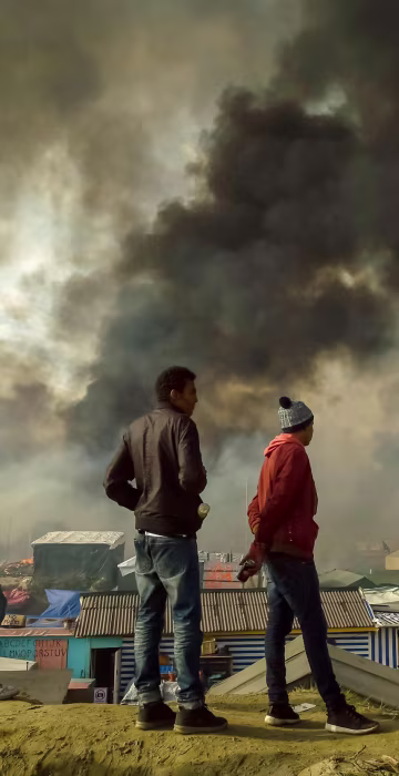 Image: Migrants stand on a hill overlooking the \"Jungle\" migrant camp in Calais