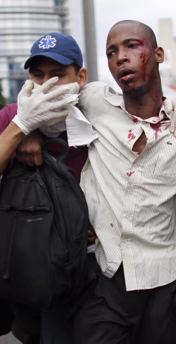 Image: Paramedics assist a man injured during clashes, April 20, 2017.
