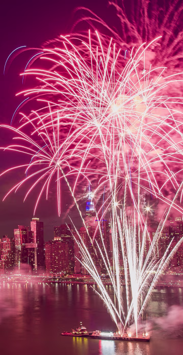 Image: With the New York City skyline in the background, fireworks explode during an Independence Day show over the East River in New York