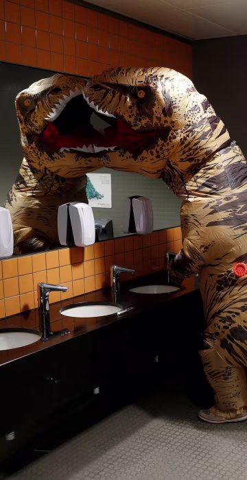 Image: Visitor wearing a T-Rex costume uses the lavatory at the London Comic Con, at the ExCel exhibition centre in east London