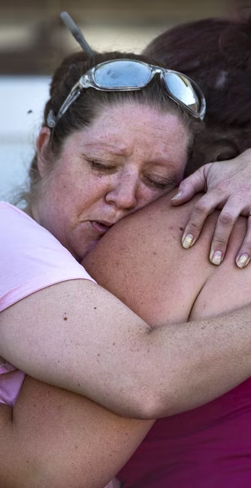 Image: Carrie Matula embraces a woman after a fatal shooting