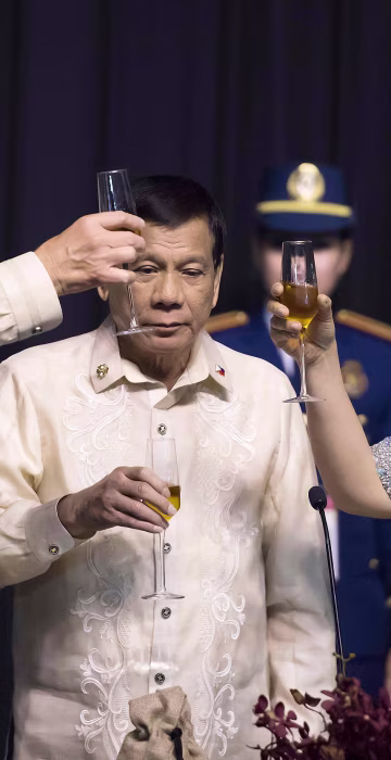 Image: Philippine President Rodrigo Duterte stands as his partner Honeylet Avancena toasts Trump during the gala dinner on Nov. 12.