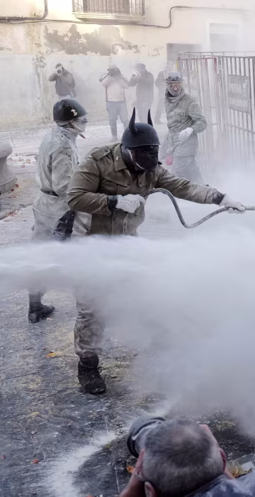 Image: Revelers dressed in mock military outfits battle with flour, eggs and firecrackers