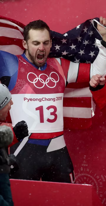 Chris Mazdzer (silver) of the U.S., David Gleirscher (gold) of Austria and Johannes Ludwig (bronze) of Germany celebrate following the luge men's singles competition on Feb. 11.