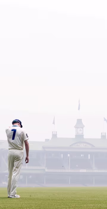 Image: Liam Hatcher of the Blues stands in the outfield amid the smoke haze from bushfires during day 3 of the Sheffield Shield cricket match between New South Wales and Queensland at the SCG in Sydney