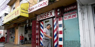 A pedestrian passes in front of a barbershop in the Barrio Obrero section of San Juan, Puerto Rico, on May 18, 2017.