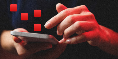 Photo illustration: A hand holding a phone that is emanating red light and graphic red squares are floating above it.
