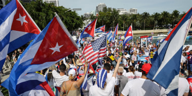 Image: People waving Cuban flags along with some people waving the American flag.