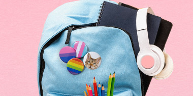 Photo illustration: Badges with the LGBTQ pride flags and a picture of a cat pinned to a school backpack.