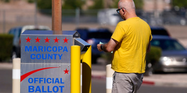 Image: A voter places a ballot in an election voting drop box in Mesa, Arizona.
