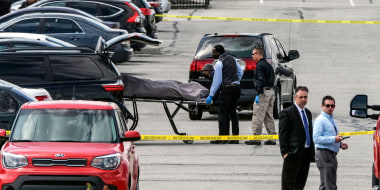 Officials load a body into a vehicle at the site of a mass shooting at a FedEx facility in Indianapolis, Indiana, on April 16, 2021.