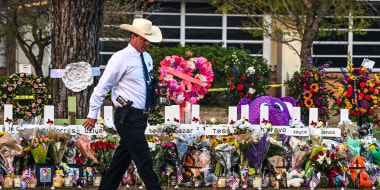 A police officer walks past a makeshift memorial for the shooting victims outside Robb Elementary School in Uvalde, Texas, on May 27, 2022.
